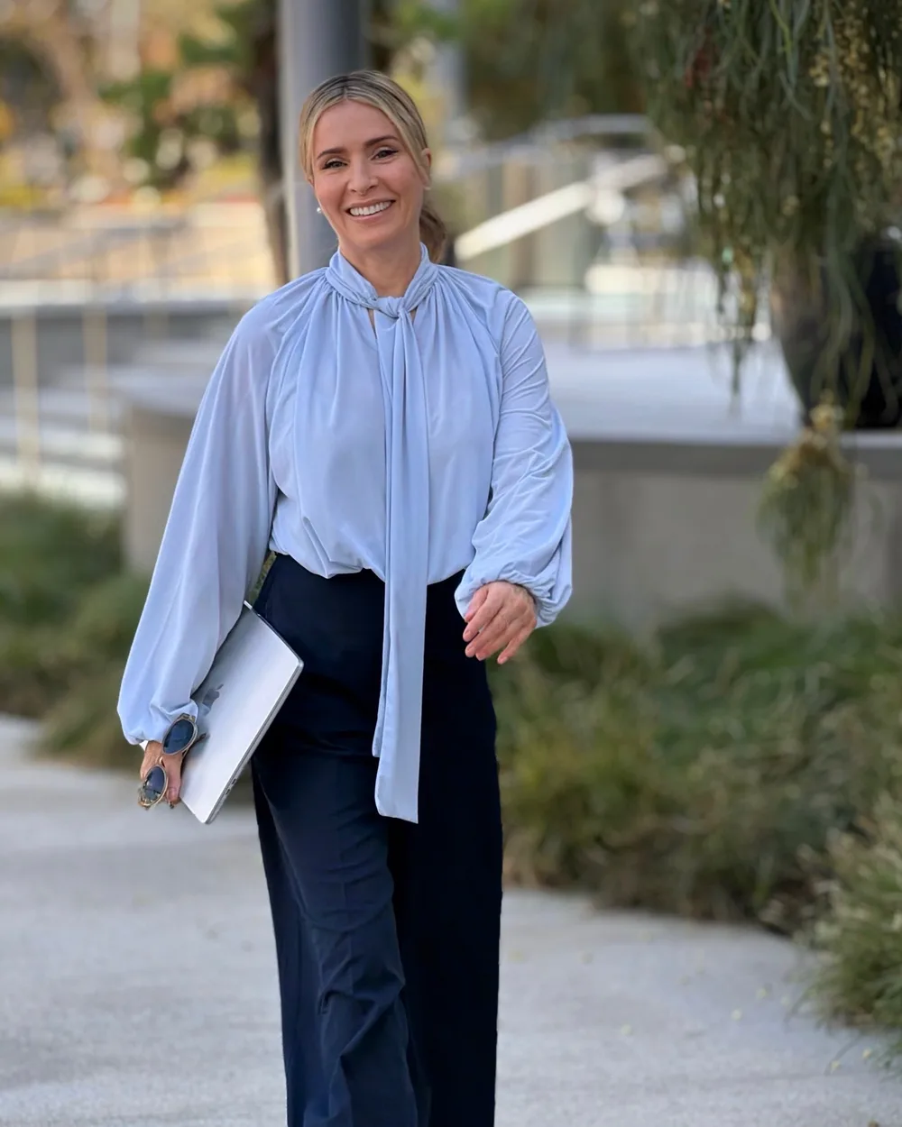 Dr. Isabell Springer smiling as she walks outdoors with her laptop